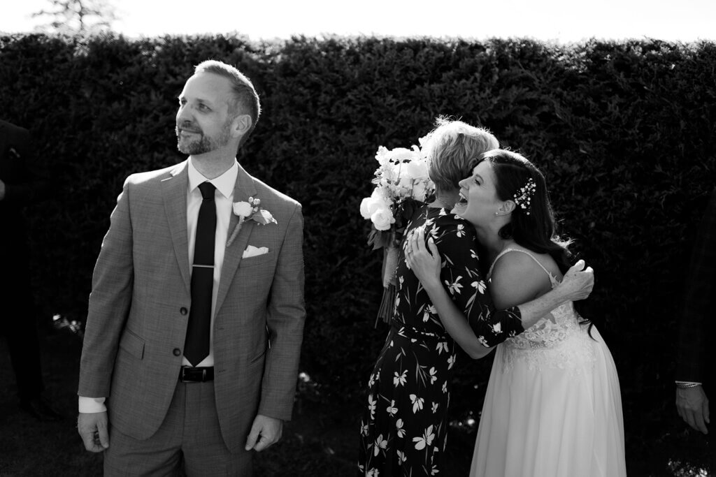 Bride hugging someone while groom looks off camera at Langtry Walk wedding